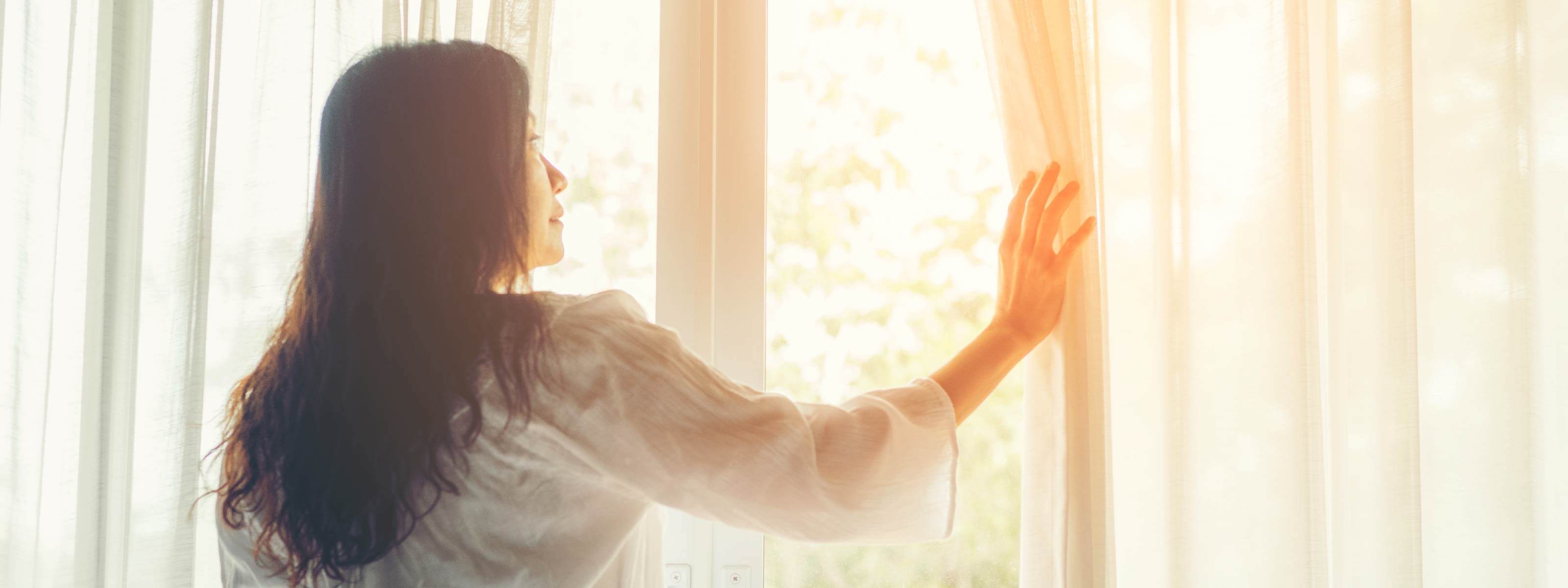 女性がカーテンを開ける様子